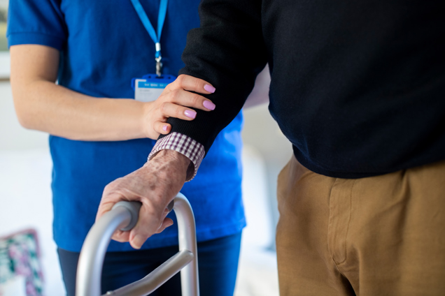 Support worker helping older man to walk